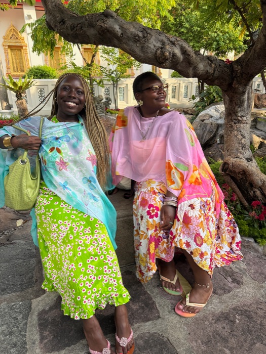 Two friends in colorful skirts under a tree